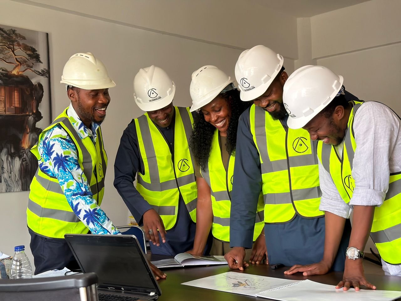 Diverse team of African engineers in hard hats and safety vests reviewing building plans indoors.
